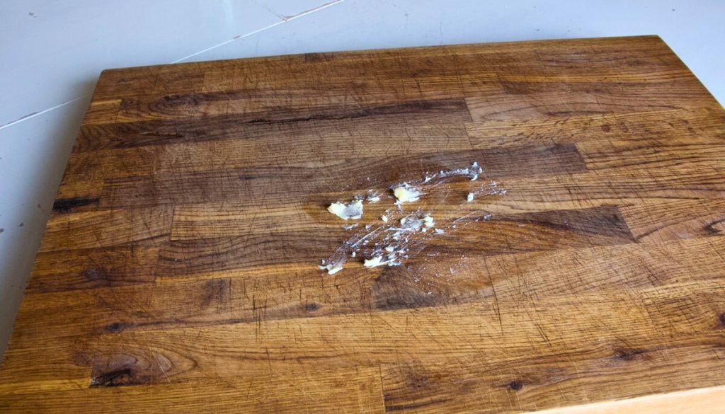 wooden cutting board on a white table with wood lube protectant on it.