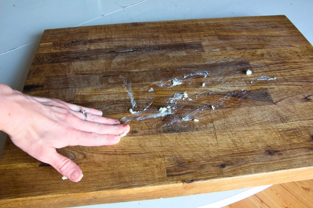 hand rubbing protective wax onto wooden cutting board