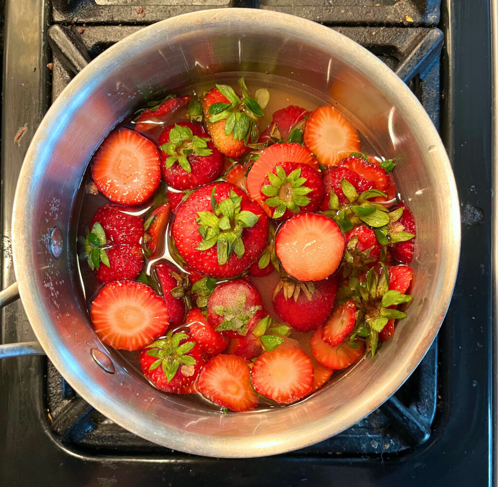 strawberry tops, sugar and water in a saucepan on the stove